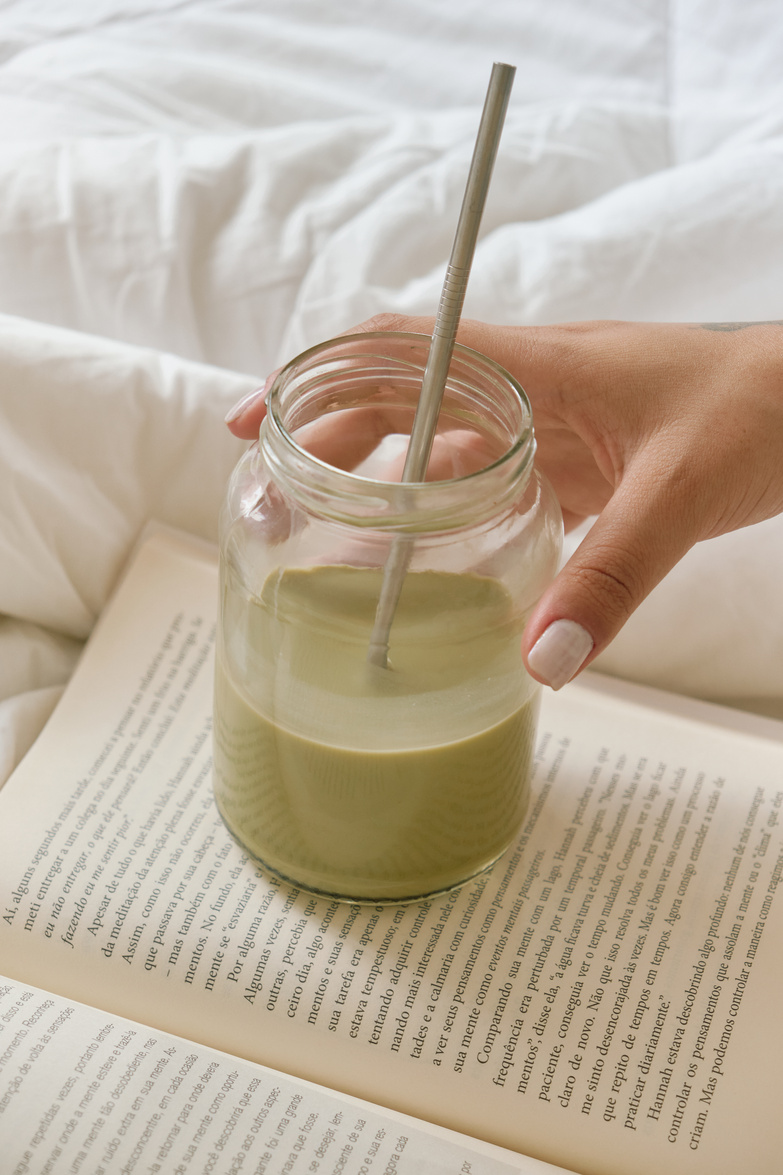 Female Hand with Glass of Drink with Straw on Book
