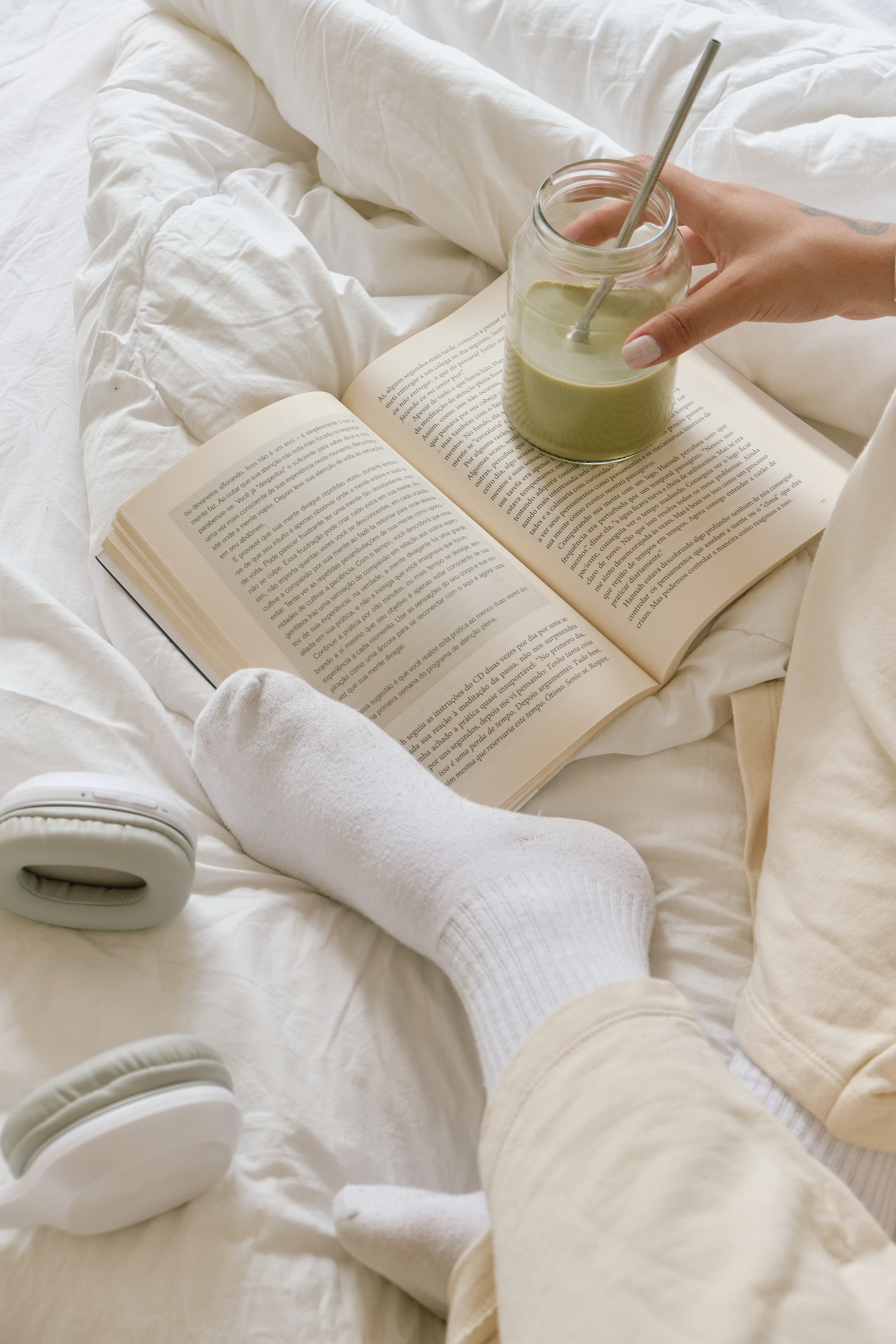 Woman with Glass of Drink, Book and Headphones on Bed