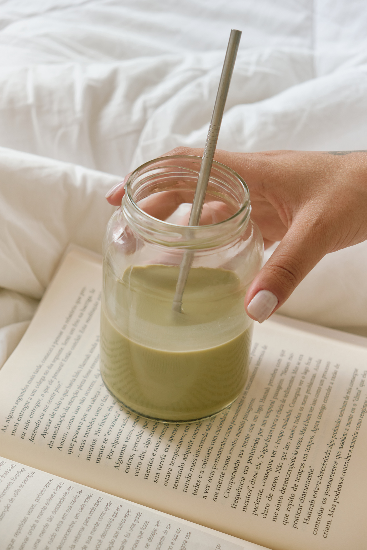 Female Hand with Glass of Drink with Straw on Book